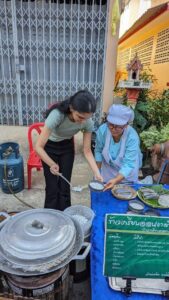 A female student learning how to make rice flour pancakes from a local lady
